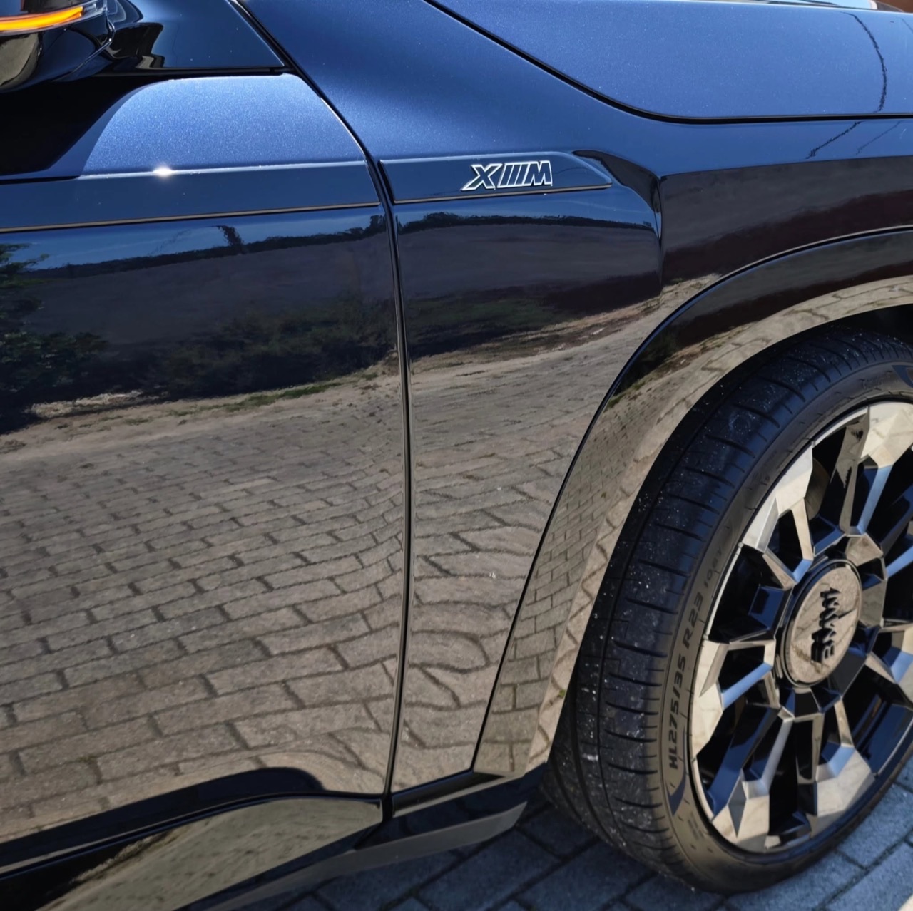 Rear quarter of the black BMW XM, crisp reflections in the paint.